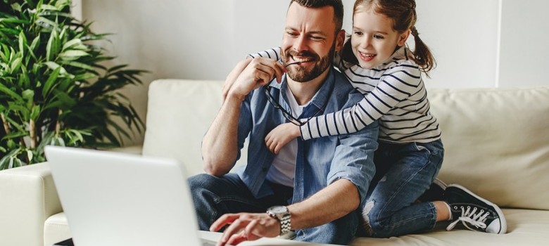 Smiling man and girl sitting on couch and looking at laptop